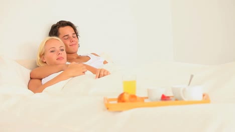 couple lying in bed with breakfast
