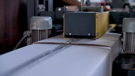 boxes being closed with adhesive tape by a sealing machine at a factory