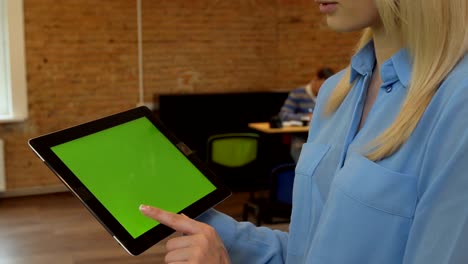 close up of young atractive woman using black tablet pc with green screen at modern office. camera stabilizer shot. chroma key.