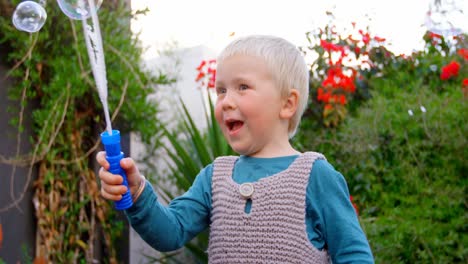 niño jugando con varita de burbujas en el jardín 4k