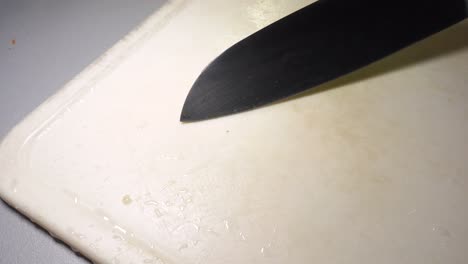 male chef slicing pickles on white surface, food preparation concept, male hands handling a large kitchen knife, nobody