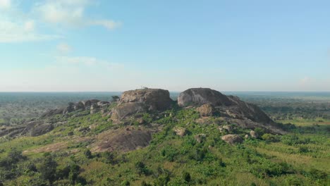 aerial shot flying backwards while looking out at large granite boulders on the east african landscape