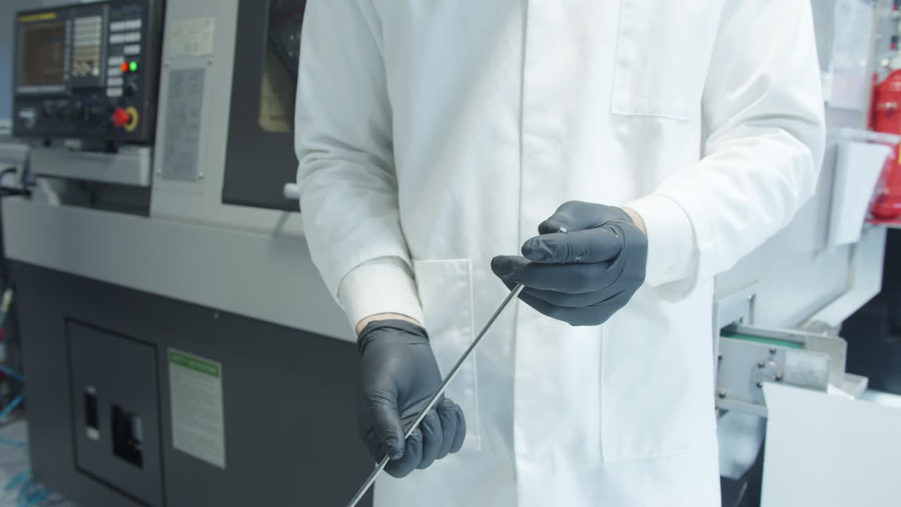 Man inspecting the quality of a titanium bar at factory.