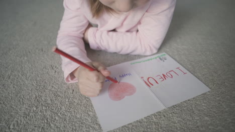 pequeña hija dibuja y colorea la tarjeta de felicitación