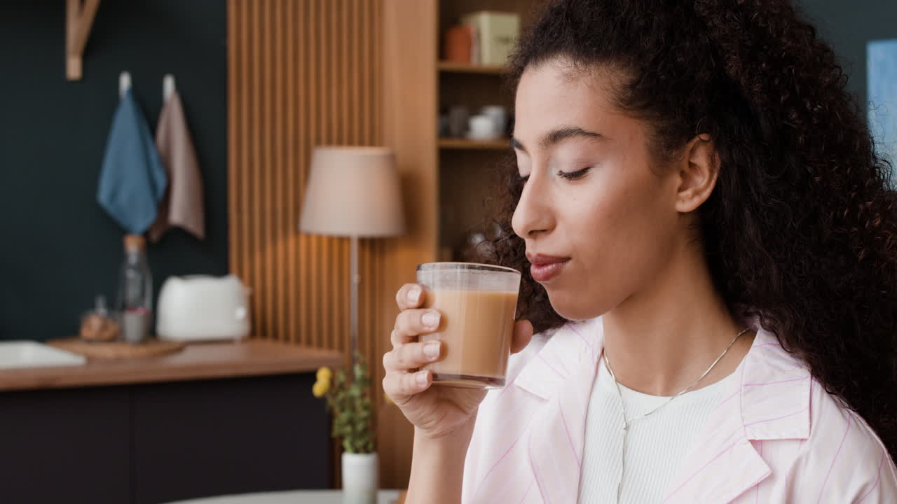 Young woman enjoying a beverage in her cozy kitchen