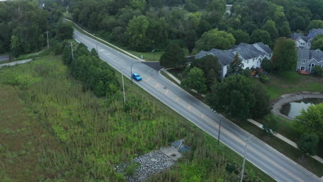 elevated aerial drone footage following a street through a scenic lush suburban landscape of middle america