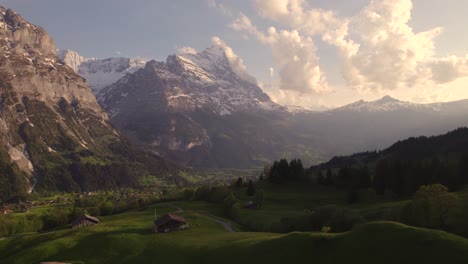 aerial drone footage dolly left to right revealing moody views of picturesque mountain village in front of eiger north face in swiss alps