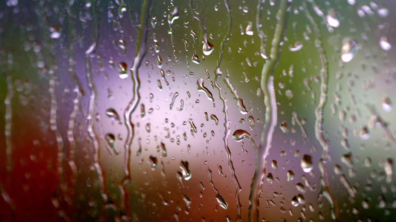 Raining weather. Rain droplets flowing on glass surface. Raindrops falling down on the window glass. Water drops on window.