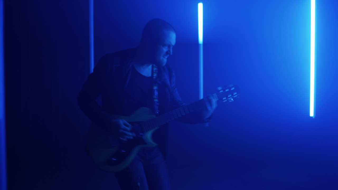 Rocker calvo che suona la chitarra vicino a luci al neon.