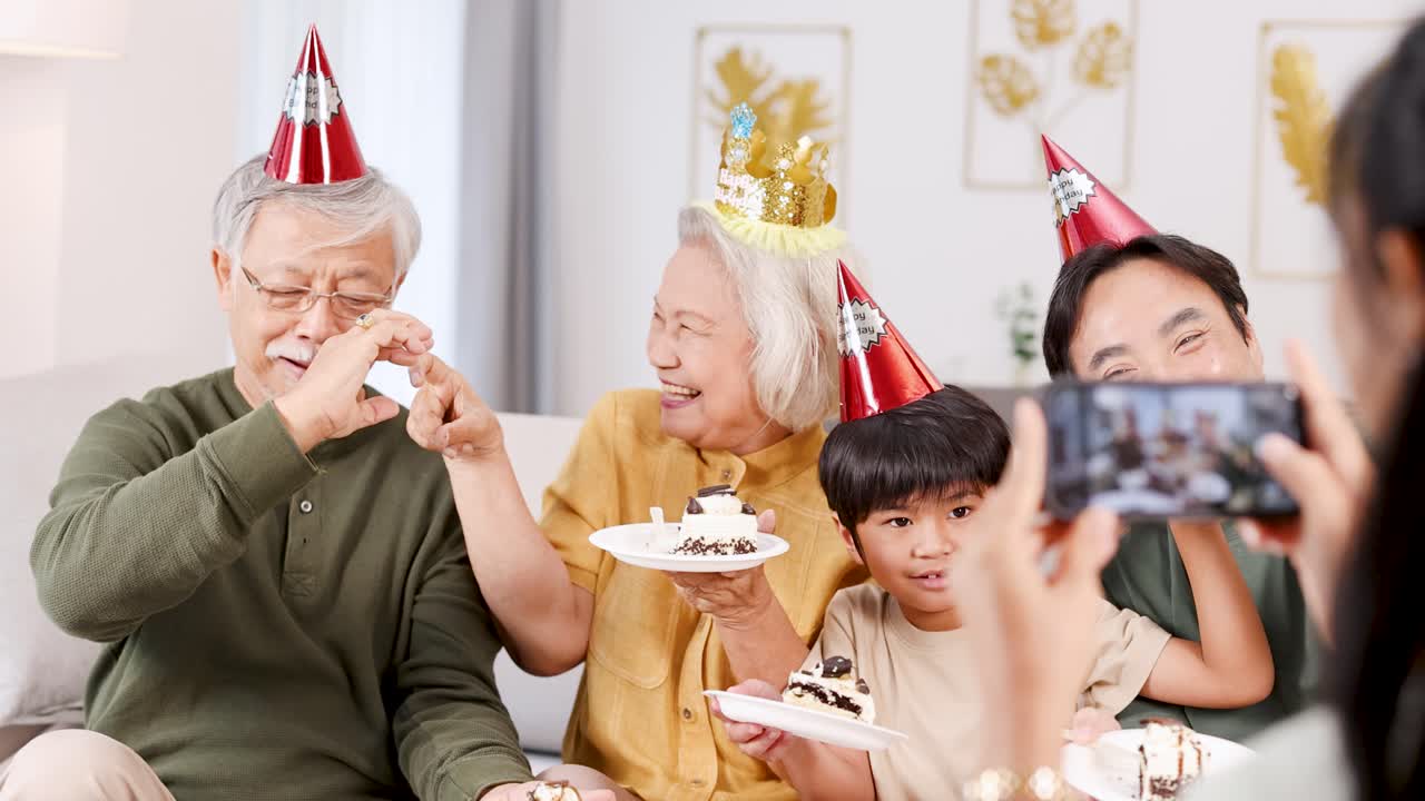 A joyful family captures a birthday moment with a selfie, featuring cake, party hats, and heart gestures