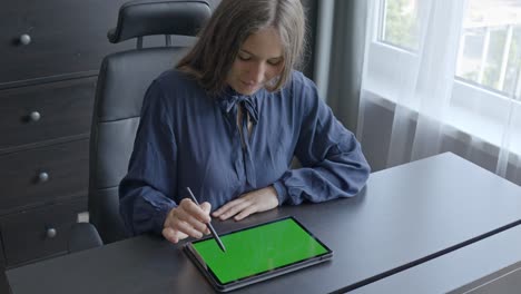 Glückliche-Frau,-Die-Im-Büro-An-Einem-Tablet-Computer-Mit-Grünem-Bildschirm-Arbeitet