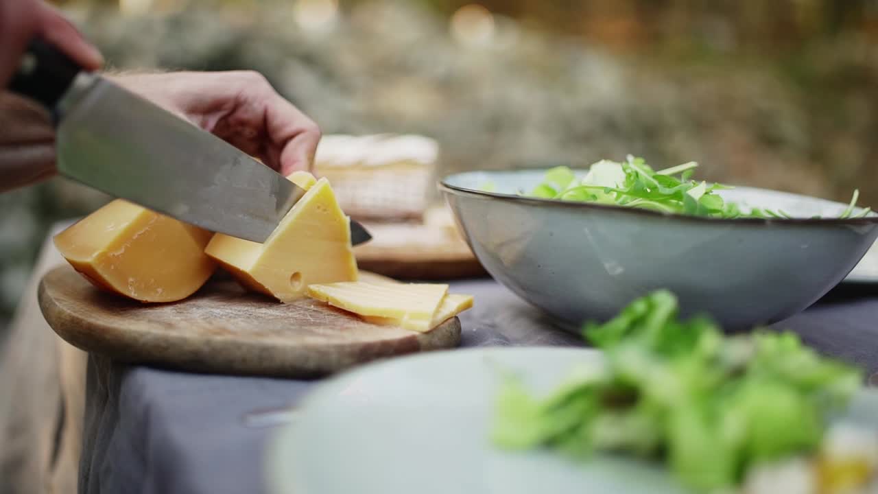 hombre cortando queso italiano para el plato de queso en la mesa