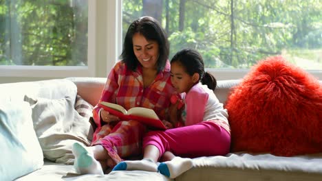 Mother-and-daughter-reading-book-in-living-room-4k