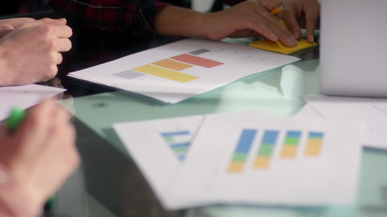 Young business woman writing notes on company statistic sheets with yellow pen