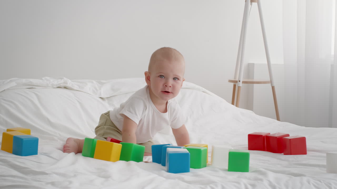 Baby playing with blocks on a bed