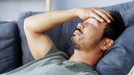 man experiencing headache on a couch