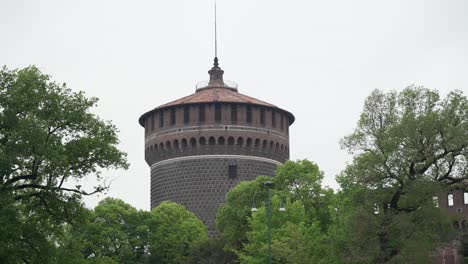 focus on sforzesco castle tower surrounded by trees of its garden