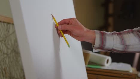 Closeup-of-a-hand-as-an-artist-begins-to-sketch-on-a-blank-canvas