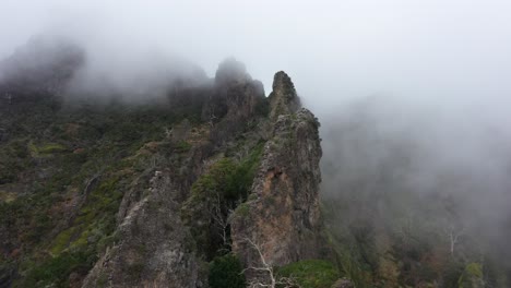 toma de drones del valle de las monjas en madeira, moviéndose a través del borde empinado de la ladera de la montaña con nubes delgadas y malhumoradas