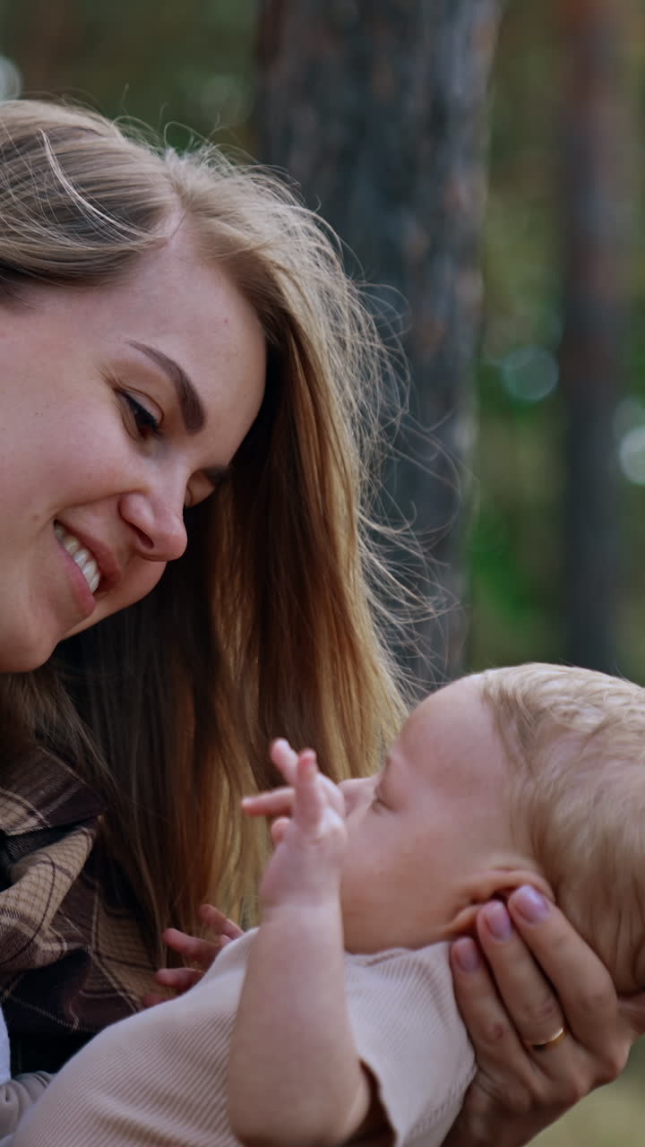 Loving mother leaning to her baby. Mom and son time spent in the nature. Side view. Vertical video