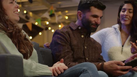 Group-Of-Friends-At-Home-Or-In-Bar-Celebrating-At-St-Patrick's-Day-Party-Looking-At-Photos-On-Phone