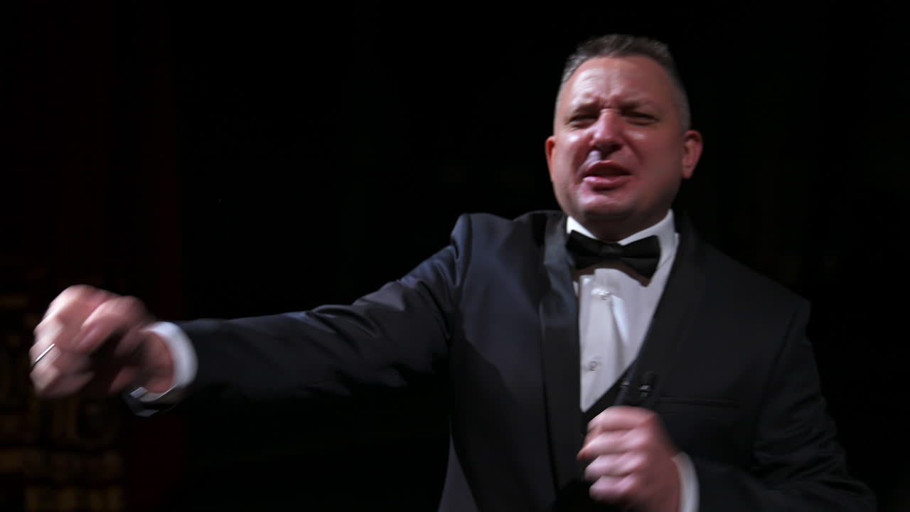 Portrait of a comedian talking. Cheerful actor in suit telling funny stories and gesticulating a lot. Man performing on stage.