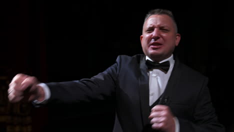 portrait of a comedian talking. cheerful actor in suit telling funny stories and gesticulating a lot. man performing on stage.