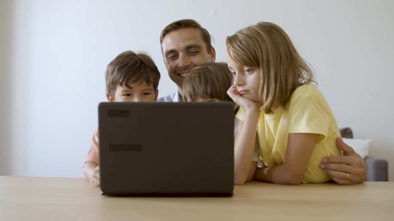 papá feliz y los niños viendo películas en la computadora portátil juntos