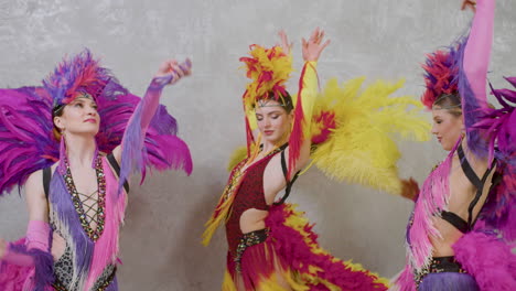 three cabaret dancers performing the choreography in colorful outfits