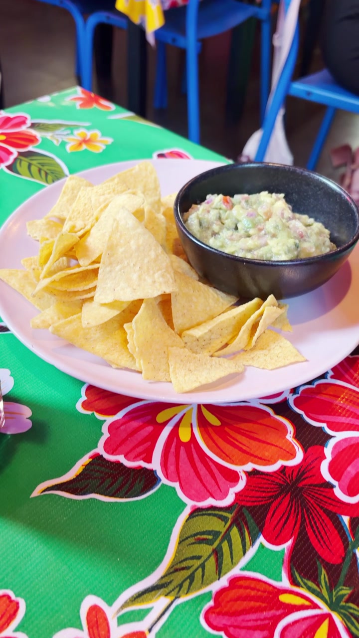 Nachos con salsa guacamole in ciotola serviti in un ristorante di strada messicano. Video verticale in stile contenuto generato dall'utente. Turista o persona del posto che pranza o cena in un luogo autentico. Appassionato di cibo o vlogger di cibo