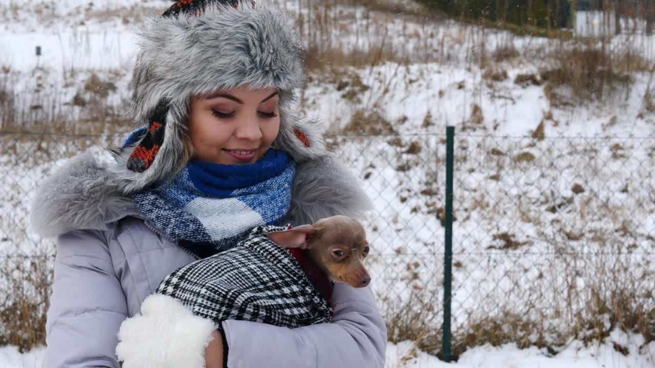 여자 는 겨울 밖 에서 작은 개 와 함께 놀고 있다