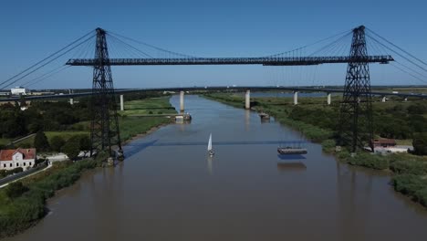 acercamiento aéreo al puente de transporte de rochefort sur mer, francia. barco de vela pasando.