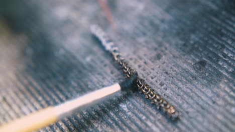 jeweler-applies-material-on-heating-chain-with-brush-closeup