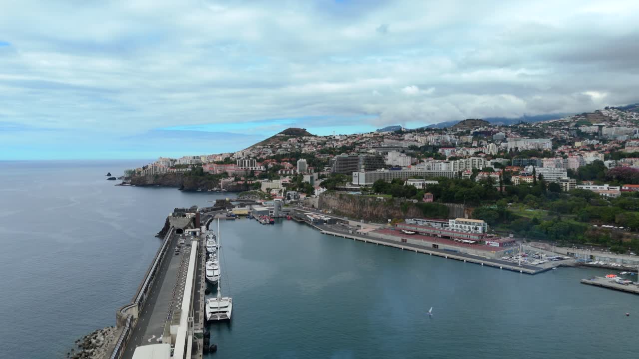 Funchal coastal city and marina in Madeira, on Atlantic coastline under blue sky. Urban island architecture and harbor infrastructure