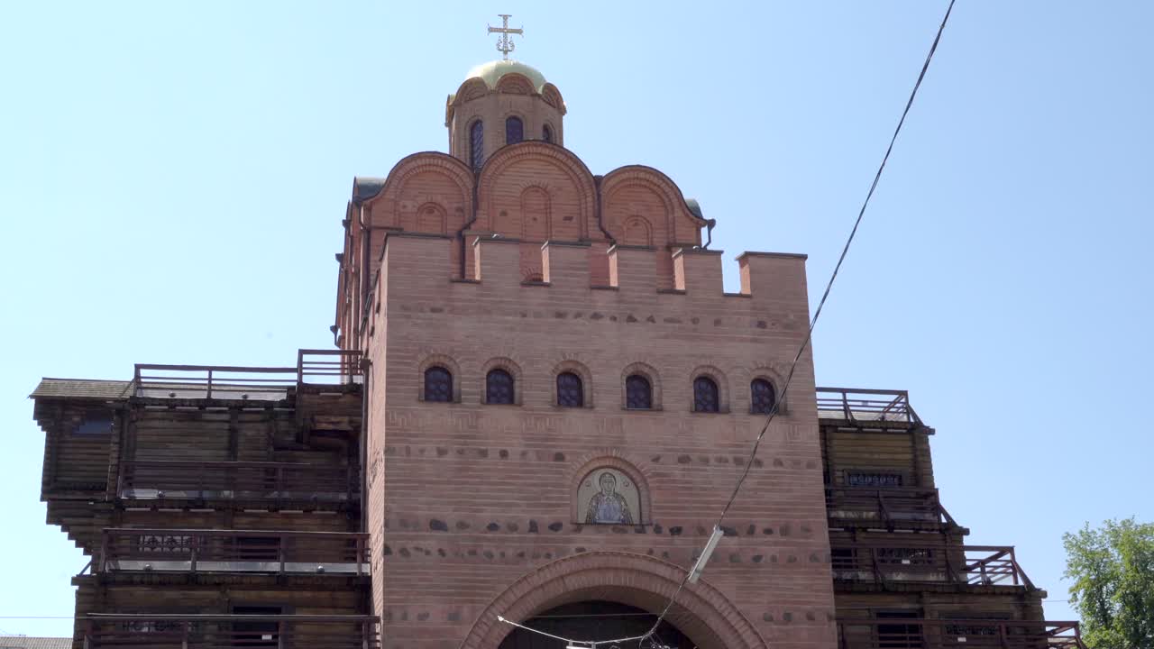 Ukraine,Kyiv,Golden Gate's entrance,Full facade of the pink brick building with wooden sides,footage starts from to top,moves to the ground level to the street with traffic and people walking around.