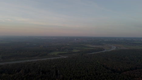 drone footage of a forest and a highway during sunset in denmark