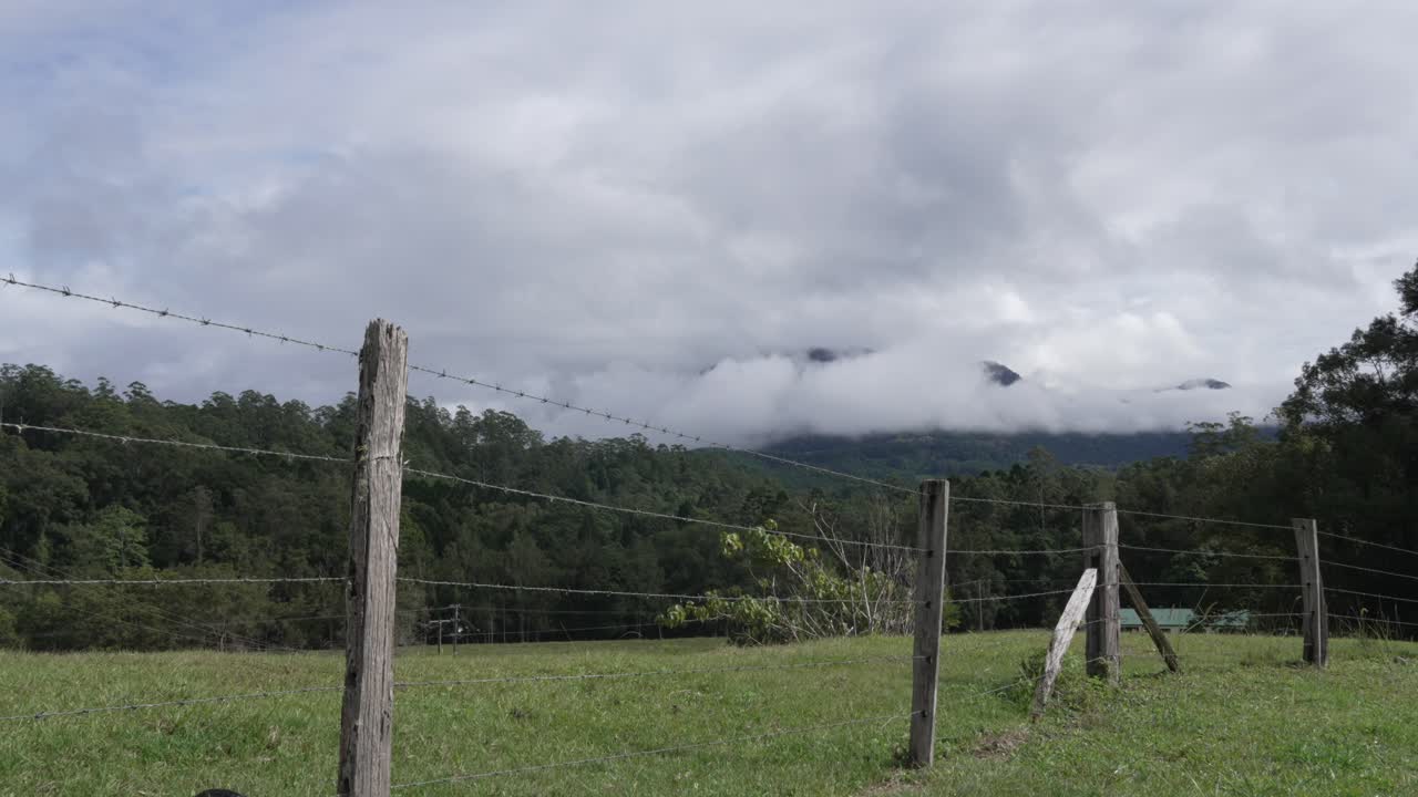 Cloudy Mountain View from a Field with a Wire Fence