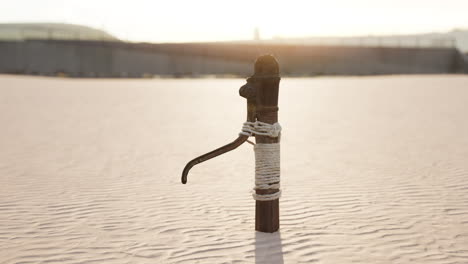 rusty old metal water pump on sand beach