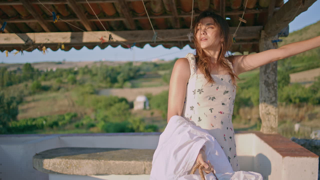 modelo relajado sosteniendo la ropa de lavado rayos de sol jardín primer plano. mujer de cabello ventoso relajante