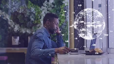 globe of network of connections against man using laptop at cafe