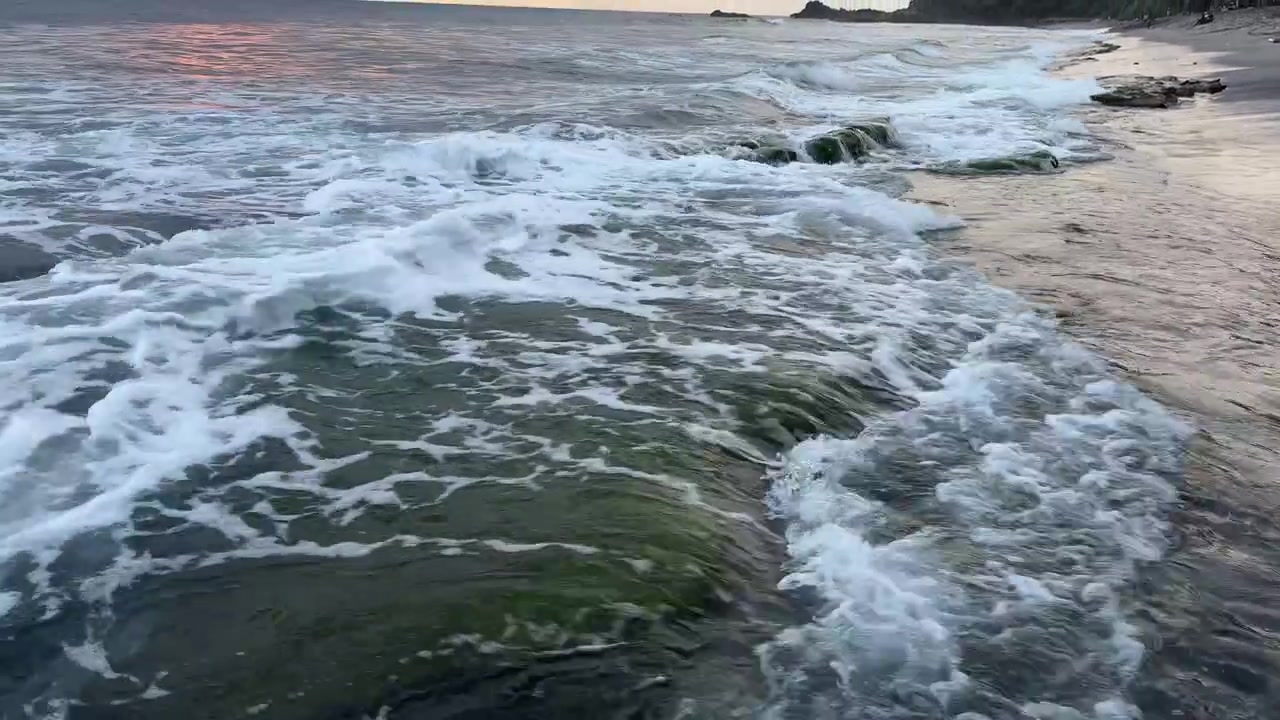 Onde oceaniche che si infrangono e si ritirano su un litorale roccioso e muschioso