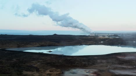piscina de escorrentía de sílice lechosa blanca en islandia con humo distante proveniente de la planta de energía