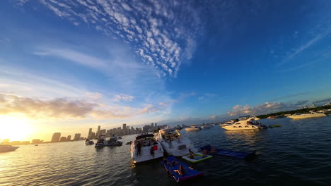two yachts stand on the anchor in the bay. people relaxing on water not far from the modern city at sunset.
