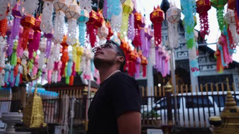 Man looking up at colorful lanterns in a temple