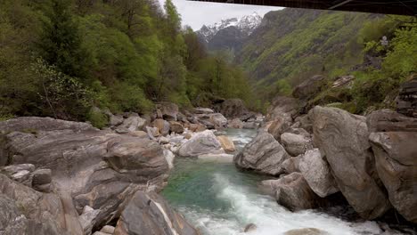 aerial dolly downstream above weathered smooth rocks in verzasca switzerland