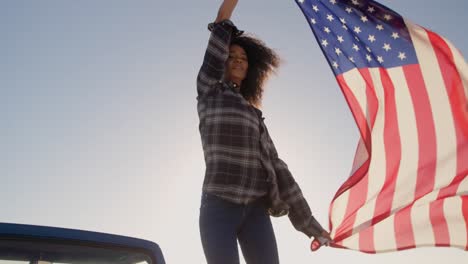 mujer de pie con una bandera estadounidense ondeando en una camioneta 4k