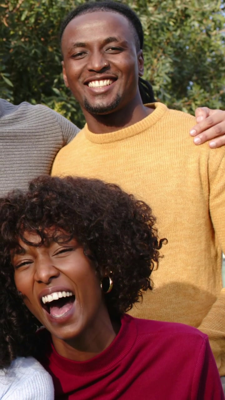 Vertical video: Cam panning showing woman laughing red top, man resting hand for portrait at park
