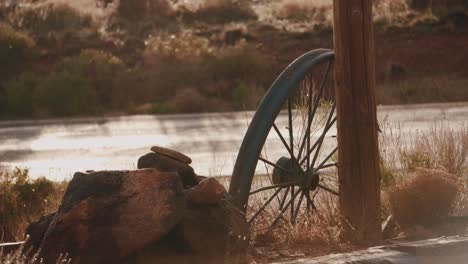 shot-of-a-wheel-of-an-old-western-covered-wagon-in-the-early-morning-light-with-a-slight-breeze-in-4k