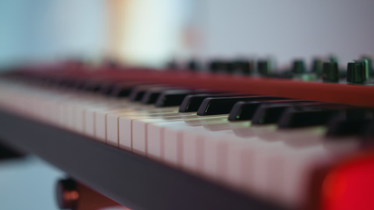 una vista en primer plano de un teclado de piano de muestreo contra un fondo borroso. la imagen se centra en las teclas, mostrando el diseño del instrumento