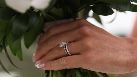 close up of brides diamond wedding ring while hold a flower bouquet in hand